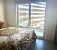 Bed with decorative pillow, sliding door with glass window, city view outside, tiled floor