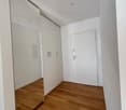 Empty room with white walls, wooden floor, large mirror, and built-in wardrobes