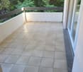 empty balcony with tile floor, railing, and a view of trees