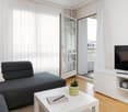 gray sofa, white coffee table, white curtains, glass door to balcony, television