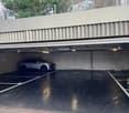 Underground parking lot, single level, gray concrete walls, 2 cars parked, fluorescent lights on the ceiling