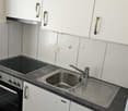 White cabinetry, tiled backsplash, granite countertop, sink with faucet, electric stove and oven, wooden floor