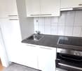 white cabinetry, tiled walls, black countertop, gas stove, stainless steel sink, dishwasher