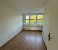 spacious room, white walls, wooden floor, white doors, large window with balcony, central heating, natural light