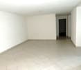 Empty room with white tile flooring, white walls, a door leading to another room