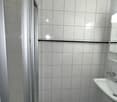 tiled floor, tiled wall, glass shower enclosure, washbasin, wall-mounted mirror