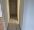 Empty hallway with white tiled flooring, white walls, door at the end