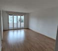 Empty room with hardwood floors, white walls, sliding glass doors leading to a balcony.