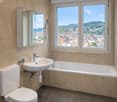 Bathroom with white toilet, sink, bathtub, shower, mirror, natural light