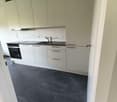 modern kitchen with white cabinets, black countertops, integrated oven, sink, faucet, dishwasher, washing machine