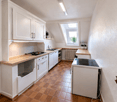 modern kitchen with white cabinets, wooden countertops, tiled floor, gas stove, sink, window, skylight