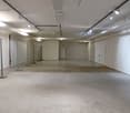 Empty room with white walls, concrete floor, metal fences, and track lighting