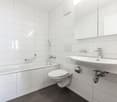 all white tiles, bathtub, toilet, sink, mirror
