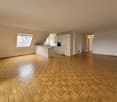 empty room with parquet floor, kitchen area with counter, cabinets, sink, oven, attic windows