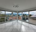 spacious, modern room with large windows, balcony, tiled flooring, view of town and mountains