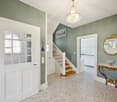 entrance hallway, white door, wooden staircase, chandelier, white floors, decorative mirror