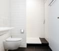 modern bathroom, white tiles, floating toilet, shower without door, black floor