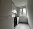 kitchen with built-in appliances, white cabinetry, tiled floor, window