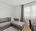 Contemporary, gray sofa, large white curtains, gray rug, white chair, desk, and table
