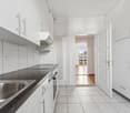 modern kitchen with white cabinets, black countertops, stainless steel sink, dishwasher, electrical outlet, and a window