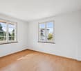 empty room, white walls, wooden floor, two windows with view of trees