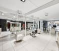 modern salon with white chairs, glass tables, mirrors, and white tiled floor