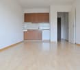 empty room, wooden floor, white walls, wooden cabinets, dishwasher, sink, kitchen area