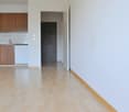 empty room, wooden floor, white walls, open door, kitchen area with sink and cabinets