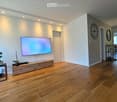 wooden floor, wall mounted television, wooden entertainment center, clock on wall