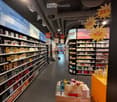 Aisle in a store with shelves full of perfume bottles, signs with discounts, and promotional items on display.