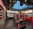 Cosmetics store with various products on shelves, a central display, and a sales counter.