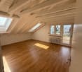 large room with hardwood floor, exposed wooden beams, skylights, sliding door with balcony