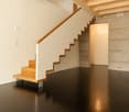 A staircase leading up to the second floor, hardwood floors, white walls, concrete walls