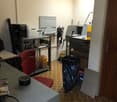 office room with red chair, tables, shelves, storage boxes, black trash bin, lamps
