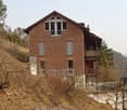 3 story brick house, on slope, 3 windows per story, balcony on the second floor