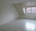 Empty room with white walls, white tiled floor, single window, slanted roof