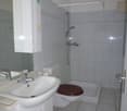 white tiles, white sink, white toilet, shower area, large mirror
