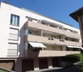 4 story building, white exterior, balconies, awnings, underground garages