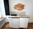 White cabinets, wooden floor, gas stove, wooden decoration on wall, built-in heater