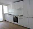 modern kitchen, white cabinets, wooden floor, stainless steel appliances, balcony