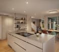 modern kitchen with island, stainless steel appliances, wooden floors, white cabinets, large windows, dining area with table and chairs