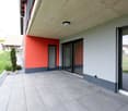 modern building with red and gray walls, large glass doors, tiled floor, and a ceiling light
