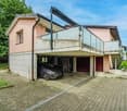 2-story house with a garage and parking space, pink exterior walls, concrete balcony, and a paved driveway leading to the garage doors