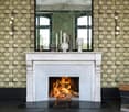 Marble fireplace with a decorative mantel, patterned wallpaper, large windows, and various decorative vases and candles on the mantel