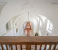 vaulted ceiling, chandelier, arch openings, wooden railing, framed picture, decorative elements, tiled floor, arch windows, red rug, furniture