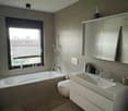 Modern bathroom with bathtub, toilet, and vanity with sink and mirror.