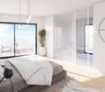 bed with grey duvet, white bedding, bedside lamps, white curtains, glass doors, white pot with green plant, clock