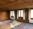 wooden walls, wooden floor, large windows, radiators, two rugs, glass coffee table