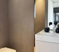 Bathroom with a white wall, toilet, sink and faucets, and a mirror.