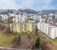 Aerial view of a residential area with many apartment buildings, yellow facades, white windows, balconies, greenery, and pathways